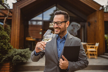 Portrait of adult man stand in front of winery hold wine and clipboard