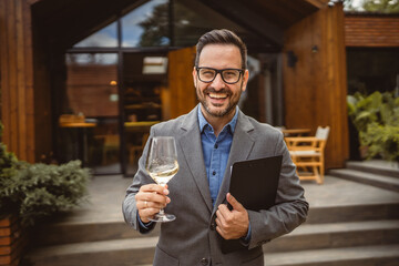 Portrait of adult man stand in front of winery hold wine and clipboard