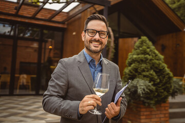 Portrait of adult man stand in front of winery hold wine and clipboard