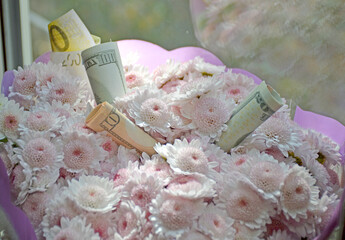 a bouquet of beautiful flowers with embedded dollar bills. gift bouquet for your beloved woman. money to buy a gift. Happy holiday
