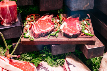 Close up delicious, fresh meat table layout raw steaks, red dry aged beef, rib eye at a butcher. Premium organic meat to sell in market. Meat industry concept. Beef slices on wooden board.