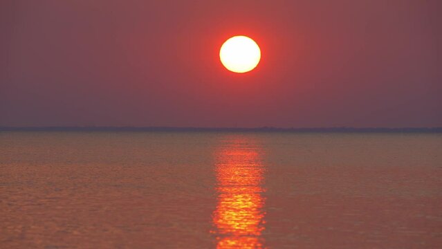 Beautiful sky cloudscape over the sea sunset. Sun set horizon over the sea. Cinematic view of beautiful evening sunset in red orange sky over sea. Sun path is reflecting in the sea surface. Nature.