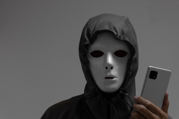 白い仮面をつけた男性とスマートフォン