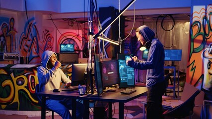 Hackers in abandoned warehouse celebrating after successfully using phishing technique that tricks...