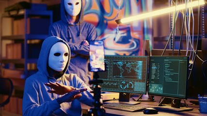 Masked hackers filming ransom video in secret HQ, threatening to release stolen data publicly if...