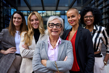 Portrait group formal business women of different ages looking smiling at camera together with...