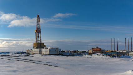 Drilling derrick and well drilling infrastructure in the northern oil and gas field. Polar snowy...