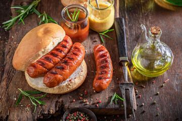 Fat grilled sausage with bun made on bonfire grill.