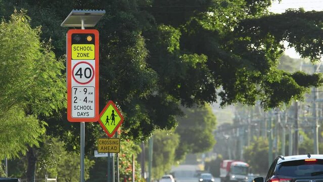 Wide shot red flashing School zone 40 km/h speed limit sign vehicles driving by QLD Australia copy space