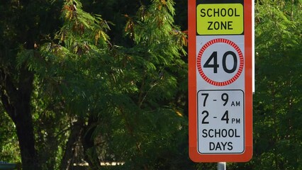 Medium shot red flashing School zone 40 km/h speed limit sign vehicle drives by QLD Australia copy space