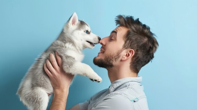 Portrait of a male holding a Husky dog over plain background