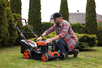 Man with modern lawn mower in garden