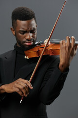 Soulful African American Man in Black Suit Playing Violin on Gray Background