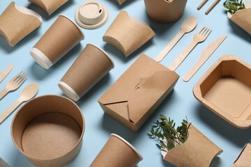 Eco friendly food packaging. Paper containers, tableware and green twigs on light blue background