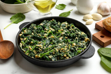 Tasty spinach dip with eggs in dish served on white table, closeup