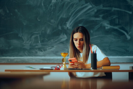 Teacher Sitting at a Desk Checking her Phone During Class. Funny unprofessional substitute teacher wasting time online 
