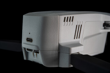 A detailed close-up view of a white drone highlighting its USB port and vents against a dark...