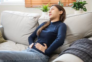 young woman gripping her stomach have abdominal pain .