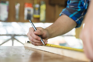 Hands of person doing diy project at home. Man measuring wood to doing cabinet craftworks as a hobby.