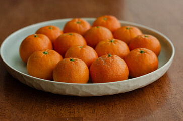 Clementine oranges in plate naturally lit arranged wooden background
