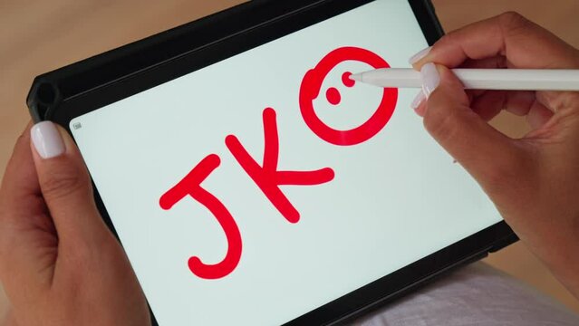 Person writing on tablet with marker JKO