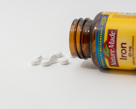 Davis, CA, 11 May, 2024. Bottle of Nature Made Iron supplement on white background, spilling, side view.   