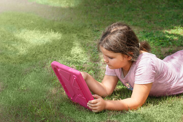 A child uses a tablet on the grass