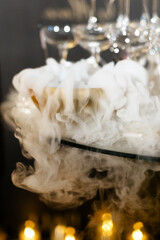 Closeup glass with white fog at dark background. Chemical reaction of dry ice with water. space for text, selective focus, party invitation, day birthday, new year, wedding, gold festive background 