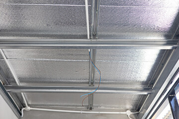 Plastic electrical conduit installed on metal sheet roof ceiling