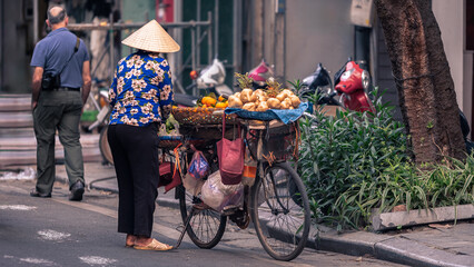 A Vietnamese street vendor woman selling tropical fruits from bicycle. Vietnam