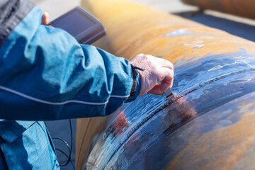Inspector is testing to weld of pipe with ultrasonic test method. Ultrasonic testing is often performed on steel and other metals and alloys.