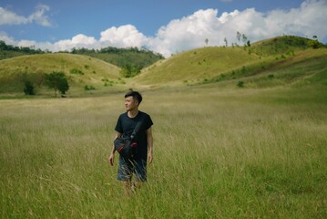 asian man walking in the field mountain in the background