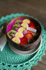 kiwi, banana and strawberry in purple yogurt in coconut shell