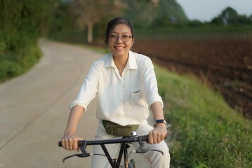 Obraz premium asian women ride a bicycle near mountain and farm