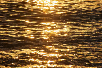 The surface of the sea glistens from the sun at sunset