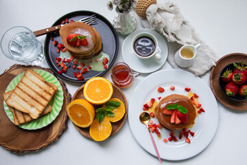 Breakfast table full of food brunch pancakes, bread and fruit