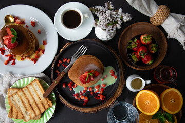 Breakfast table full of food brunch pancakes, bread and fruit