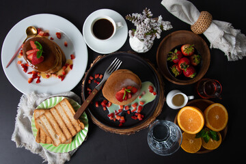 Breakfast table full of food brunch pancakes, bread and fruit