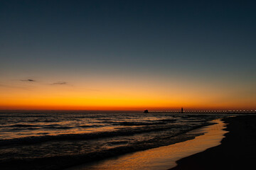 A golden horizon fades to deep blue sky as the sun sets over Lake Michigan at Grand Haven, Michigan