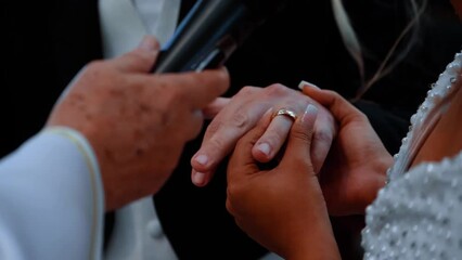 Close up of bride's hand putting a wedding gold ring on the groom's finger. Action 60fps