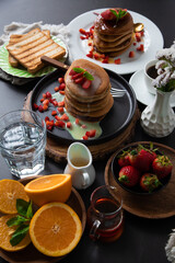 Breakfast table full of food brunch pancakes, bread and fruit