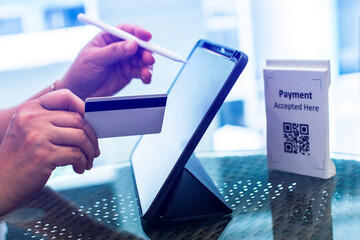 Cashier staff using tablet to receive orders from customers at counter service in cafe or store with QR code and smart card or credit card. Cashier takes payment from customer.