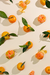 Fresh juicy orange yellow tangerines as minimal flat lay pattern, Sweet Citrus fruits with green leaves on beige table background. Still life geometric pattern of mandarin oranges overhead, above