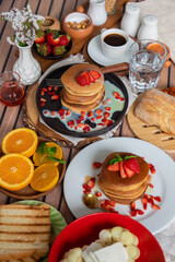 Breakfast table full of food brunch pancakes, bread and fruit