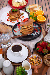 Breakfast table full of food brunch pancakes, bread and fruit
