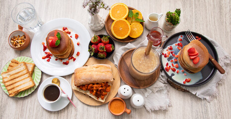 Breakfast table full of food brunch pancakes, bread and fruit