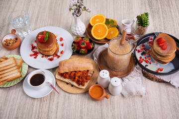 Breakfast table full of food brunch pancakes, bread and fruit