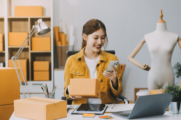 Asian SME business women use laptop computer checking customer order online shipping boxes at home....