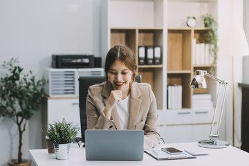Asian Businesswoman Using laptop computer and working at office with calculator document on desk, doing planning analyzing the financial report, business plan investment, finance analysis concept.