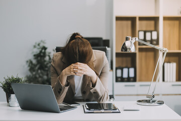 Asian women sitting in an office With stress and eye strain Tired, portrait of sad unhappy tired frustrated disappointed lady suffering from migraine sitting at the table, Sick worker concept